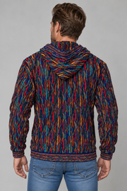 A man viewed from behind wearing a hooded sweatshirt with a vibrant multicolor abstract pattern in red, blue, yellow, and orange, paired with blue jeans against a solid gray studio background.