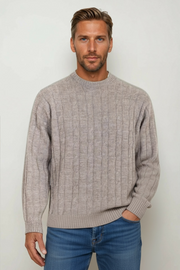 Man wearing a beige sweater and blue jeans against a white background