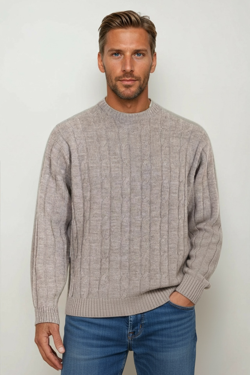 Man wearing a beige sweater and blue jeans against a white background