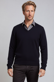 Man wearing a dark blue sweater over a gray shirt with a light gray background
