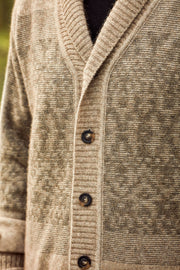 Close-up of a textured knit cardigan sweater in a warm taupe-beige color, featuring a V-neck, dark brown buttons, and a subtle woven pattern.