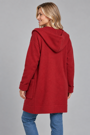 A woman wearing a red hooded coat, shown from the back, paired with blue jeans against a solid gray studio background.